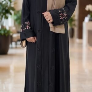 Black abaya with pink floral embroidery on the sleeves and black floral embellishments on the front, styled with a beige hijab | Azmira Collection